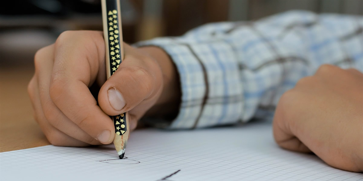 mano di bambino che scrive con la matita