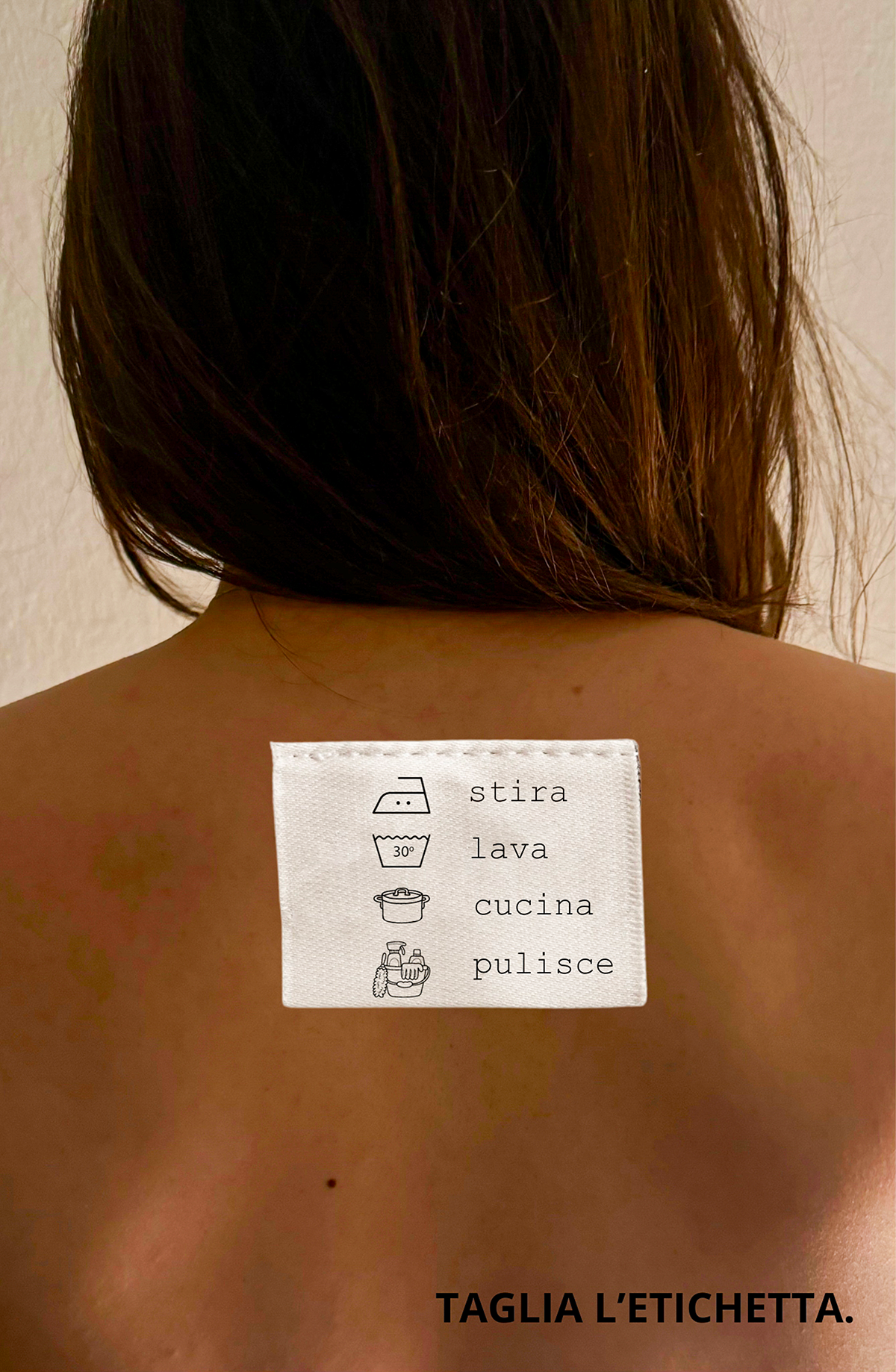 donna che riporta sulla schiena un'etichetta: "Stira, lava, cucina, pulisce" e sotto l'invito: "Taglia l'etichetta"