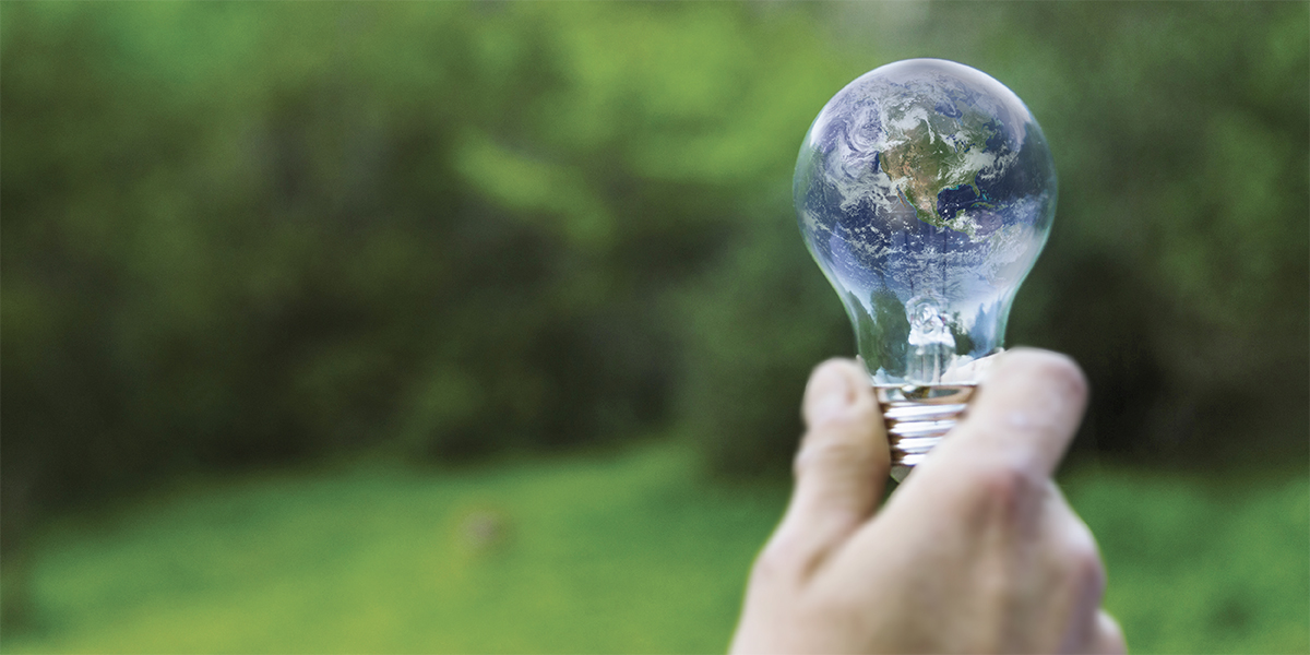 mano che regge una lampadina contenente il pianeta terra