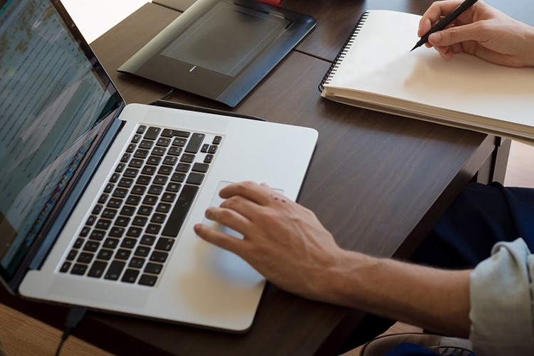 Dettaglio della locandina: uomo che guarda il computer e scrive su carta