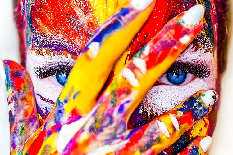 Dettaglio della locandina: volto di donna e mano dipinta di molti colori
