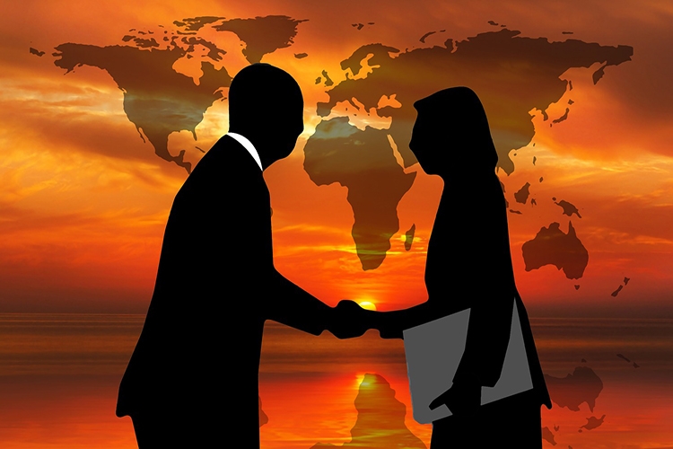 persone che si stringono la mano con una mappa del mondo sullo sfondo