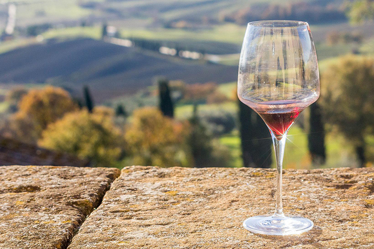 bicchiere di vino e panorama collinare sullo sfondo