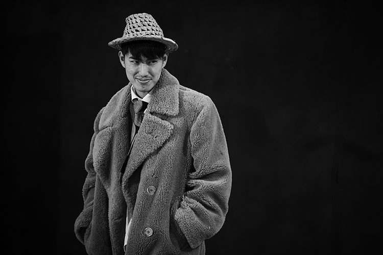 una foto della mostra: attore con cappello e cappotto