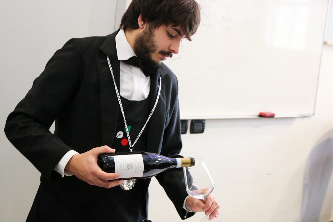 somellier che versa il vino in un bicchiere